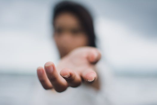 A soft focus image highlighting a reaching hand, symbolizing connection or help.